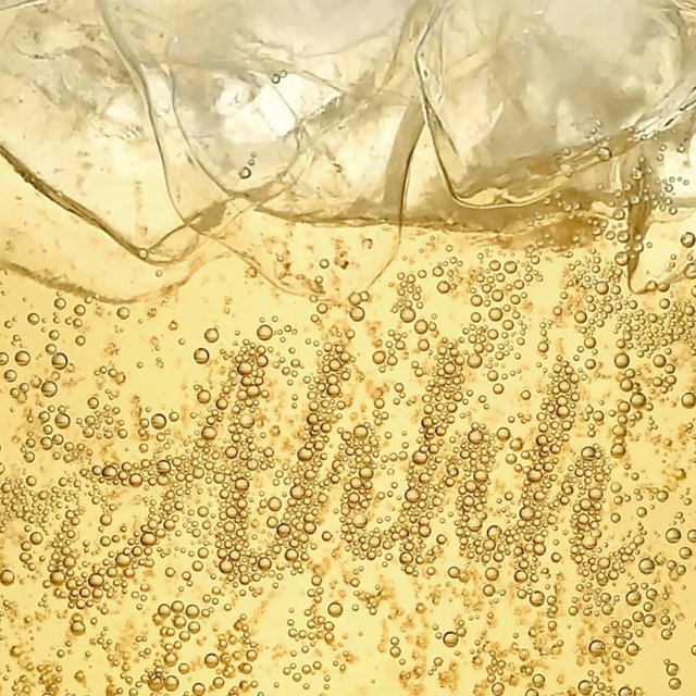 Close-up of sparkling ginger ale bubbles in a refreshing golden drink