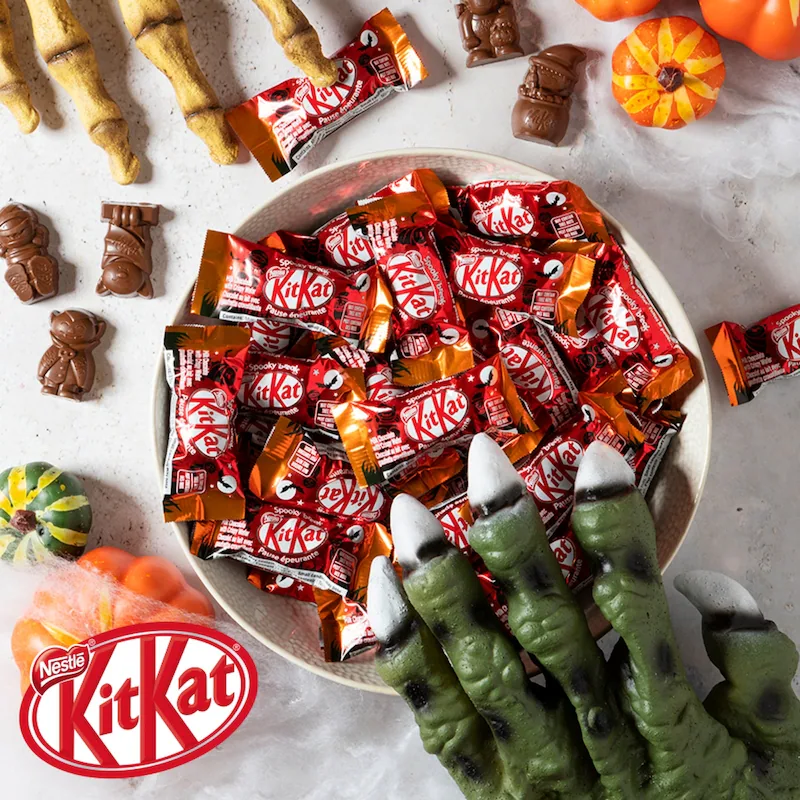 Bowl filled with individually wrapped KITKAT Halloween Scary Friends mini bars surrounded by Halloween-themed chocolate treats