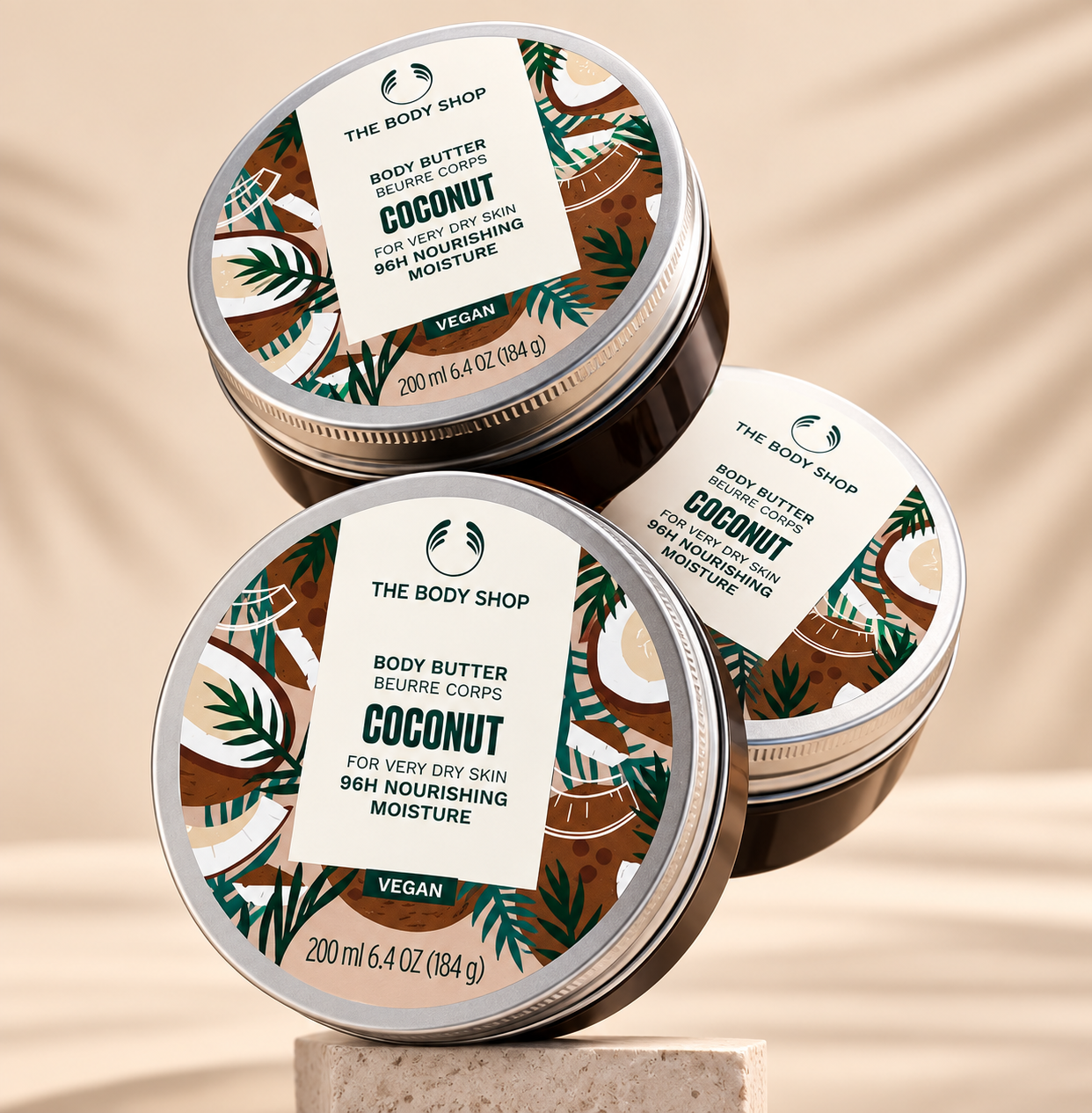 Three The Body Shop Coconut Body Butter tins arranged on a pedestal